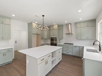 Sage green shaker-style kitchen with a white island and timber floor
